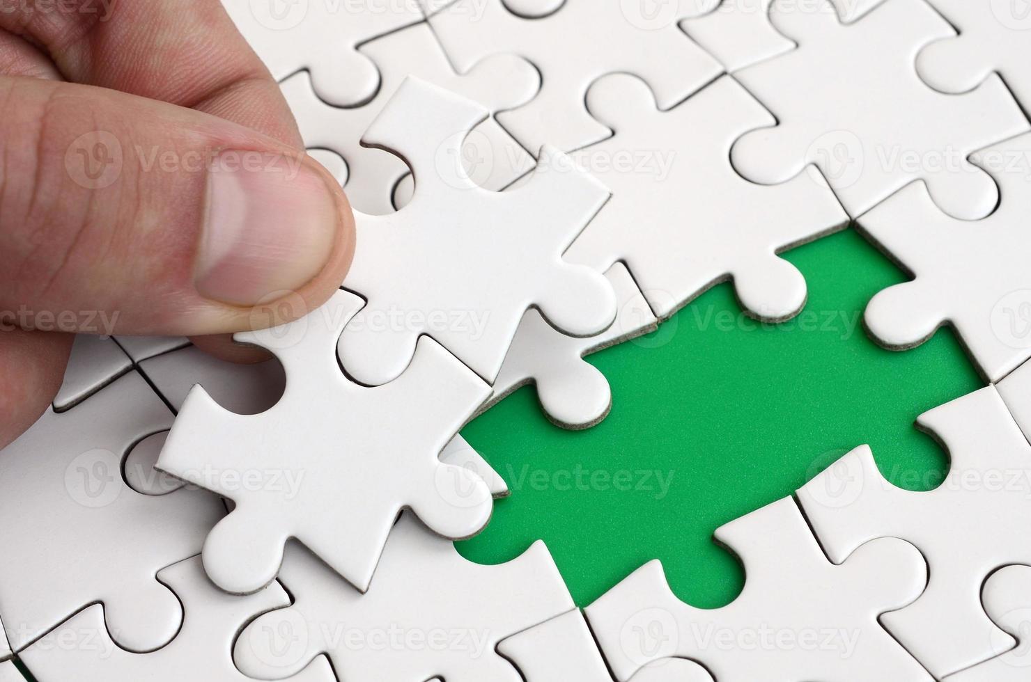 The human hand fills the last missing elements of the surface from the jigsaw puzzle. The concept of the completion of the initiated cases photo