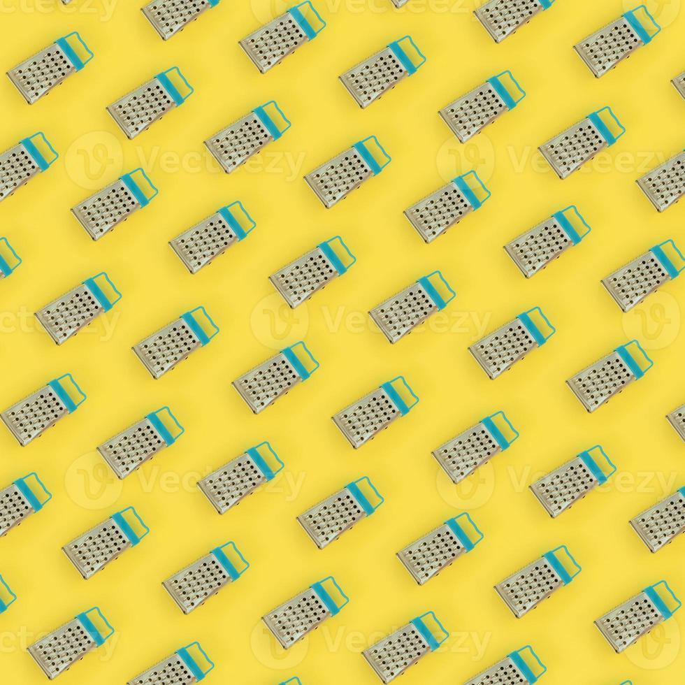 Small stainless steel graters lies on a pastel colored paper. Kitchen accessories. Tools for cooking. Flat lay top view photo