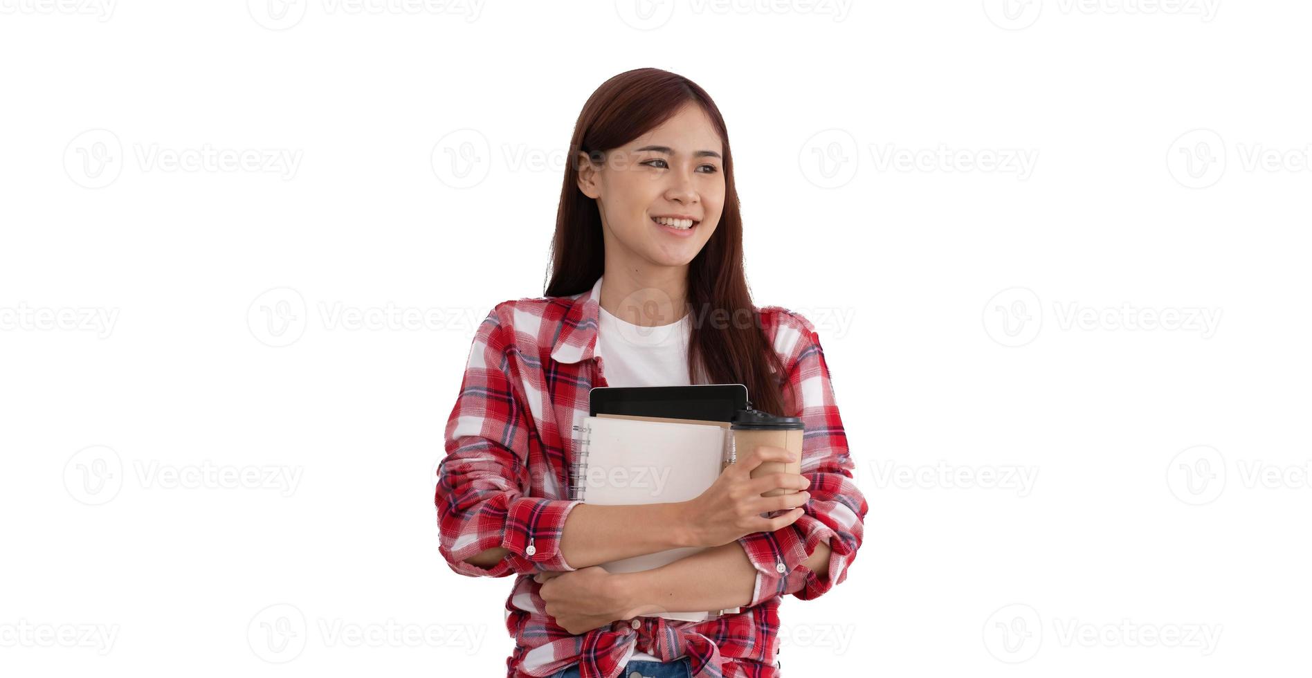 Portrait of an attractive young asian university student or college student in red Scott shirt holding a coffee cup, tablet and notebook standing over white background photo