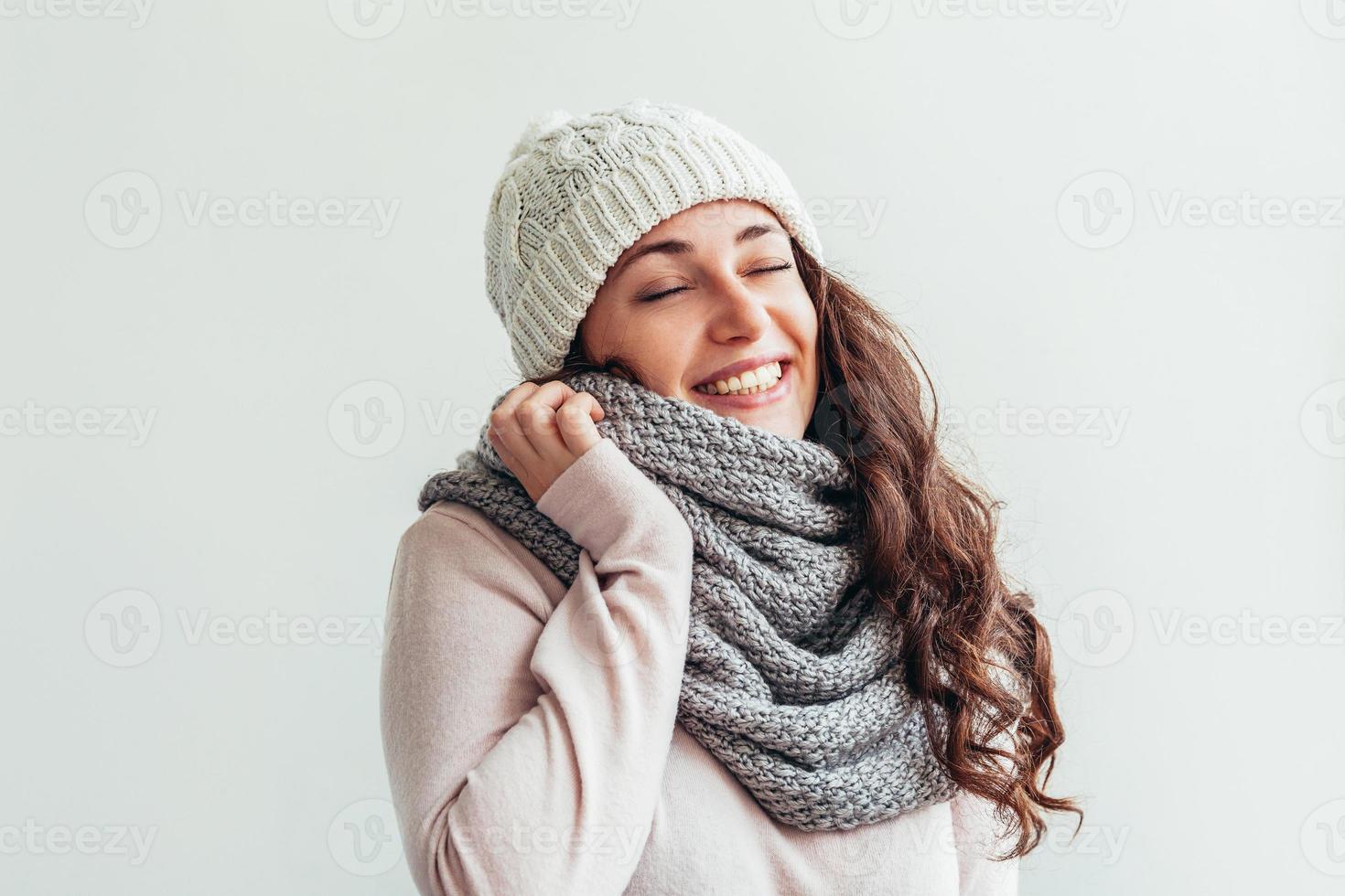 Chica riendo vistiendo ropa de abrigo sombrero y bufanda aislado sobre fondo blanco. foto