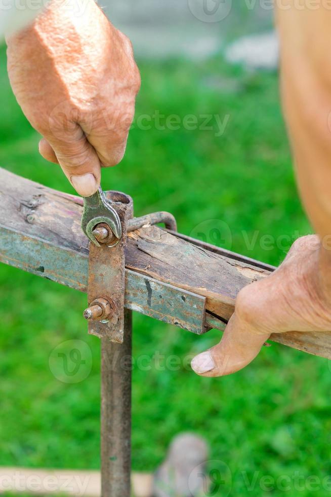 Elderly man twists the nut by wrench photo