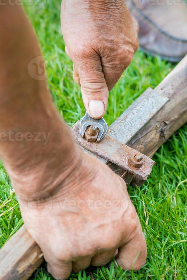 Elderly man twists the nut by wrench photo