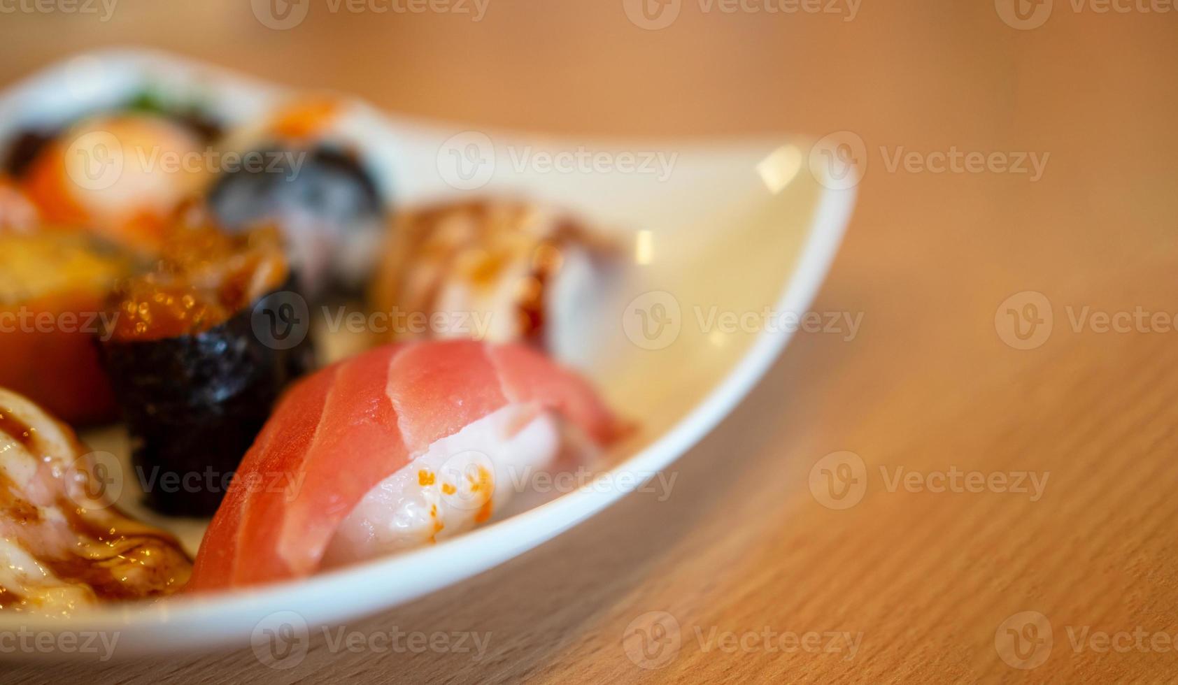 varios sushi en un plato blanco colocado sobre una mesa de madera foto