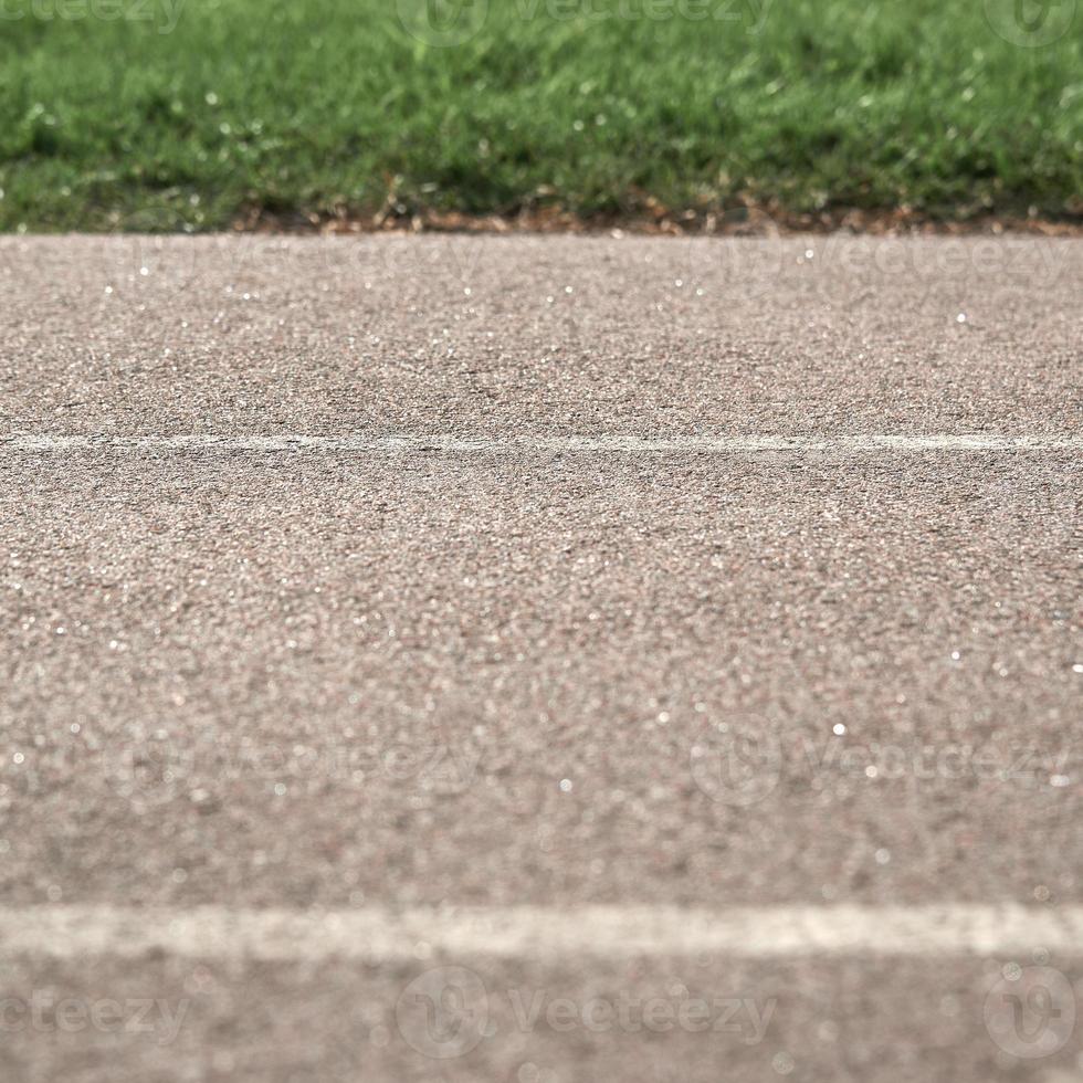Texture paved road with markings on the background of green grass. Part of the photo is in blur.