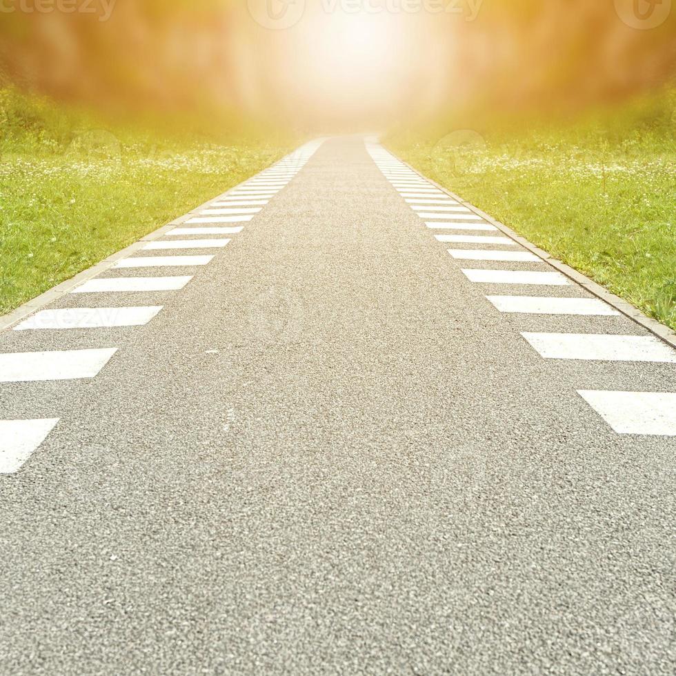 Bicycle path lit by bright sunlight in the Park closeup going into the distance. photo