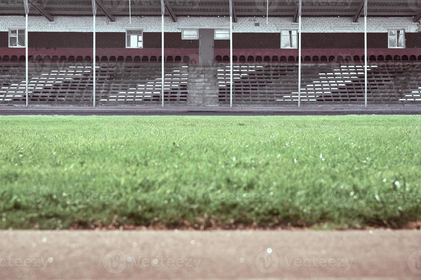 Empty audience seats at the stadium. In the foreground is a green field in blur. photo