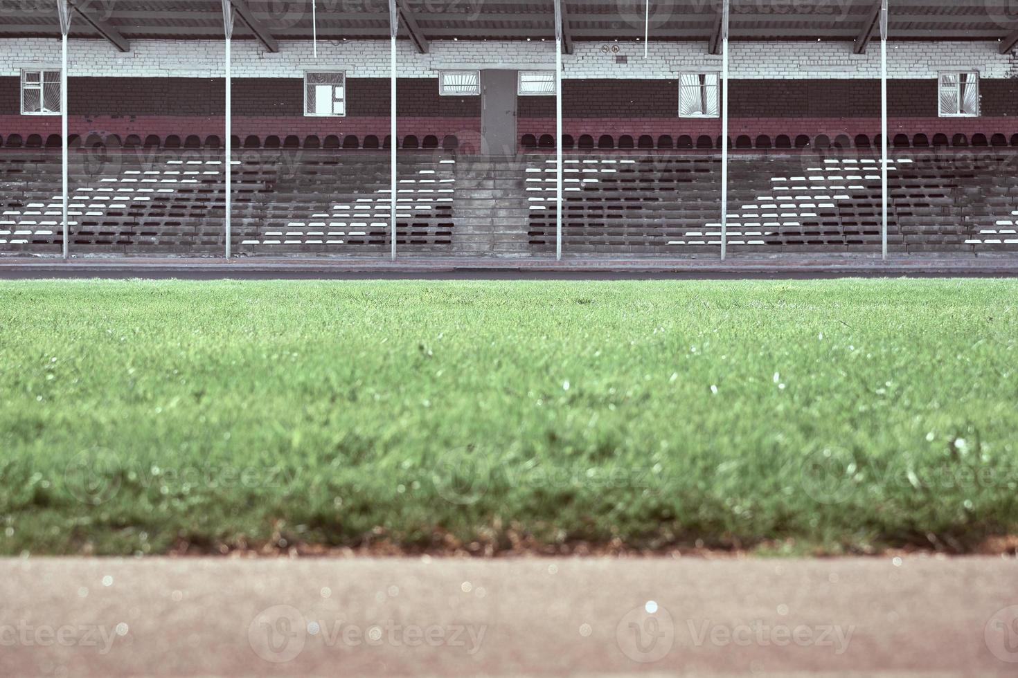 Empty audience seats at the stadium. In the foreground is a green field in blur. photo