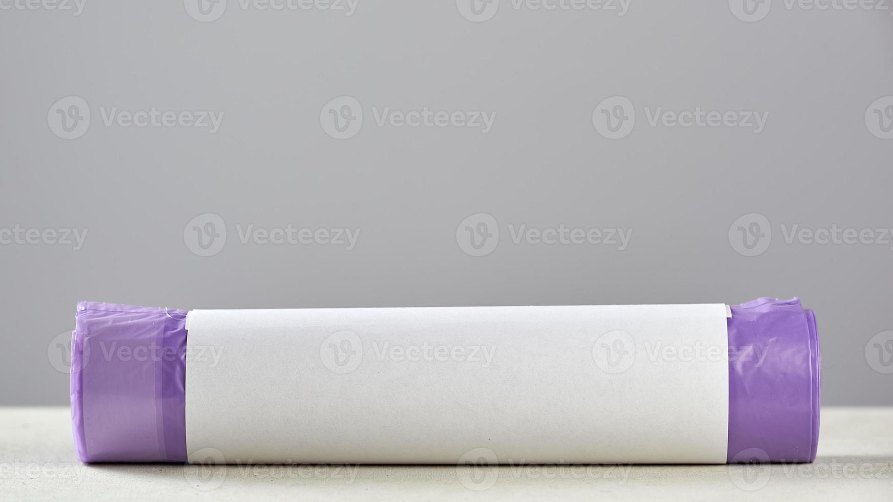 Roll purple garbage bags with copy space on grey background. photo