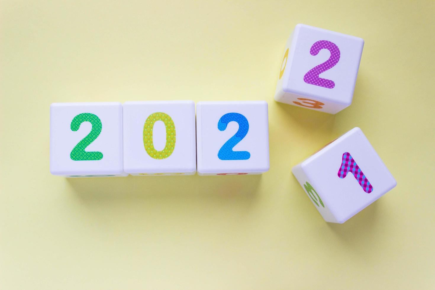 Cubes with colorful numbers on a yellow background. Year change concept, from 2021 to 2022. Digit 2 pops out digit 1. New year, calendar photo