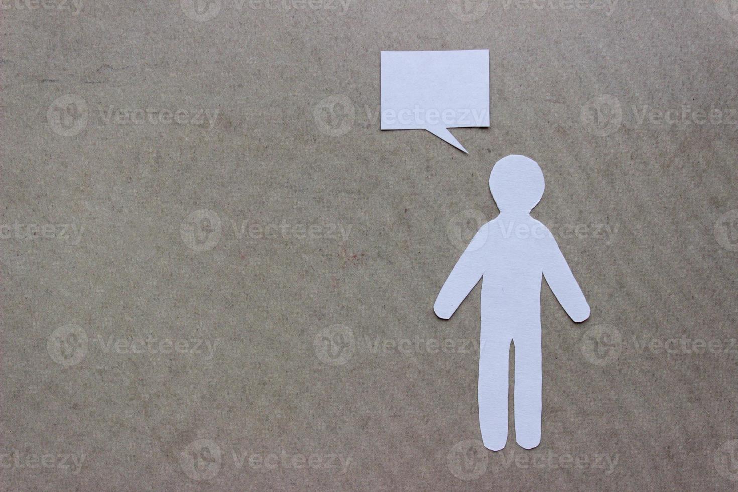 Silhouette of man cut out of white paper. With speech-bubble and copy space on a beige background photo