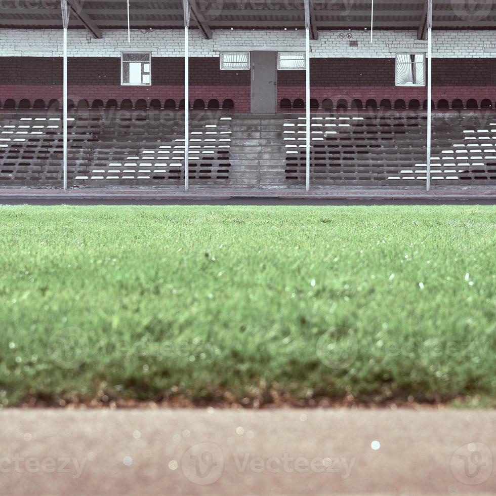 Empty stands at the stadium. In the foreground is a green field in blur. photo