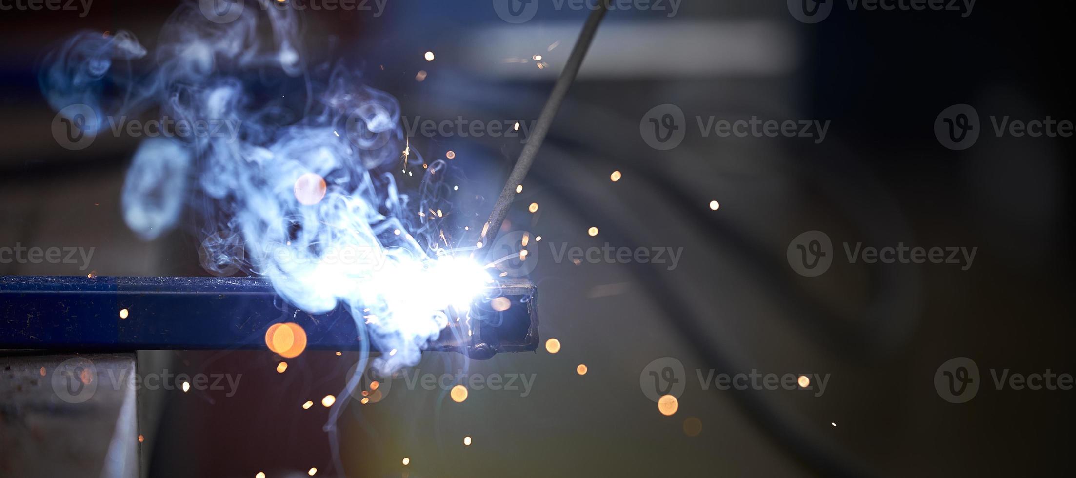 The connection of two parts by welding close-up. Sparks and blue light when welding. photo