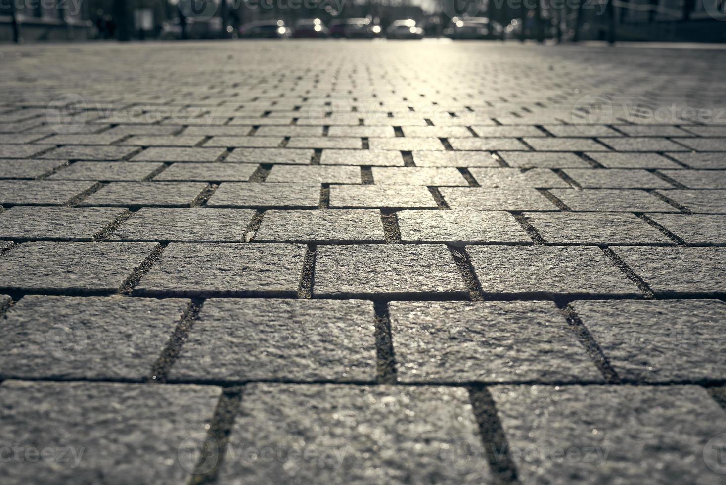 Paving tiles background. Paving slabs close-up on the background of cars in the blur. photo