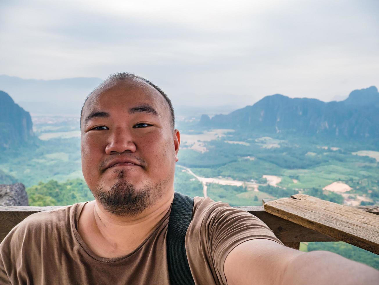 foto de retrato de turista gordo con hermosa vista en el pico de pha ngeun en la ciudad de vangvieng laos. ciudad de vangvieng la famosa ciudad de destino de vacaciones en lao.