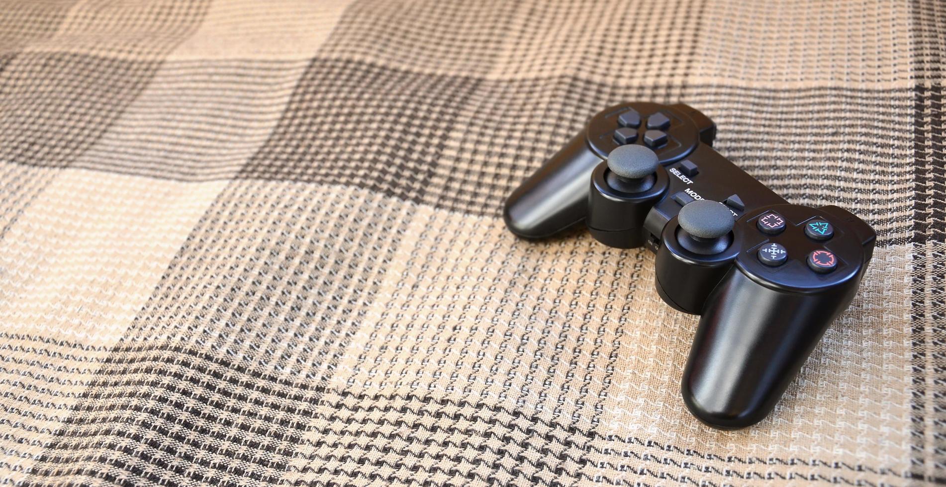 Video game controller lies on a checkered plaid photo