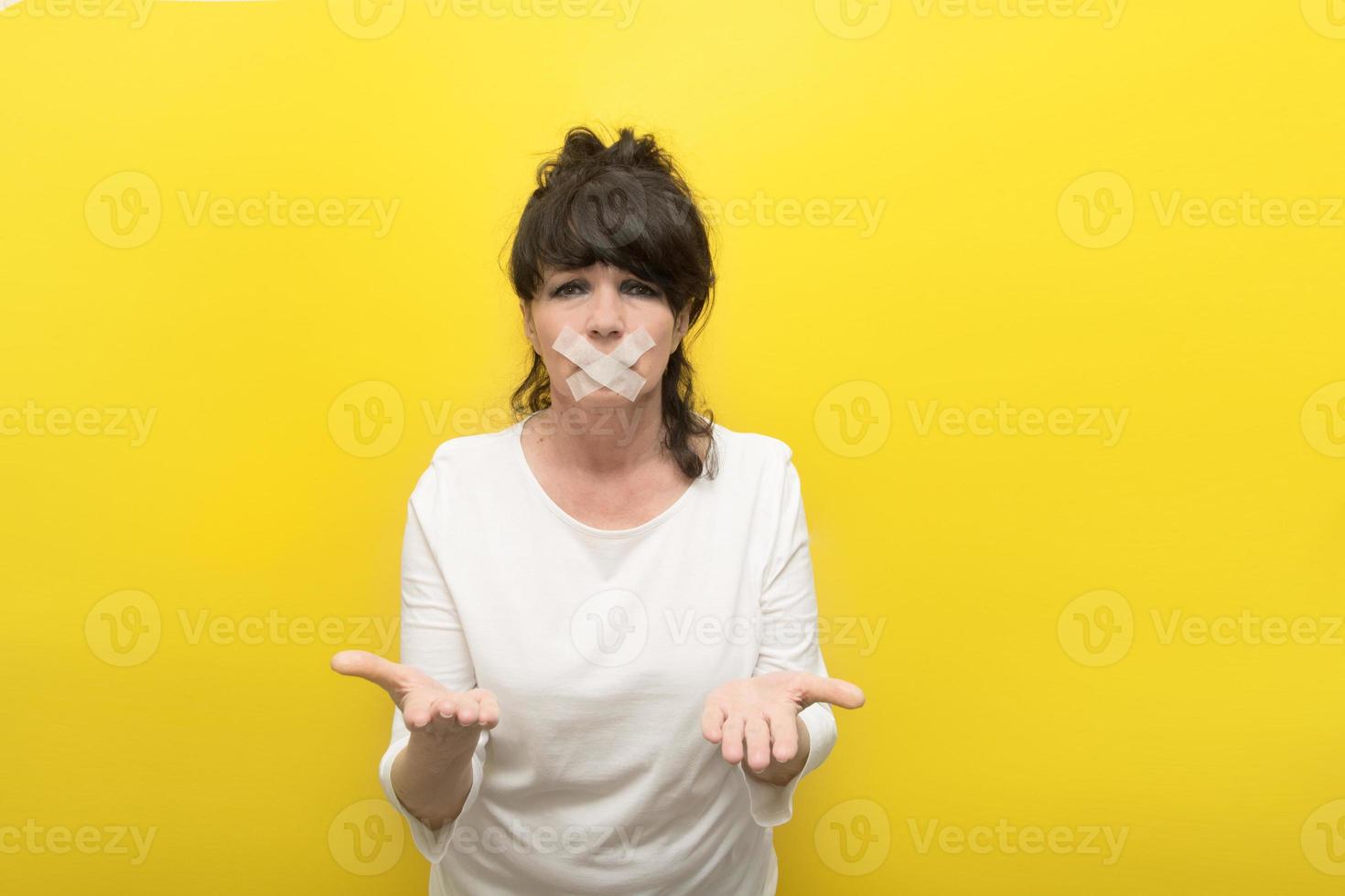 aged woman with a sealed mouth and outstretched arms in a begging gesture, the concept of tyranny, despotism, censorship, asking for help photo