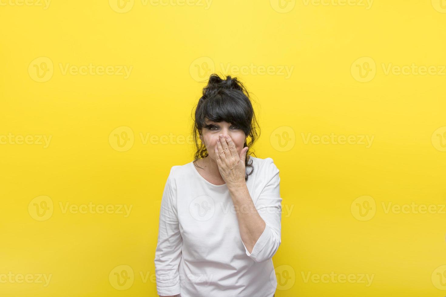 mujer de fondo amarillo se cubrió la boca con la mano de emociones desbordantes, el concepto no puede creer, ¿es realmente cierto? foto
