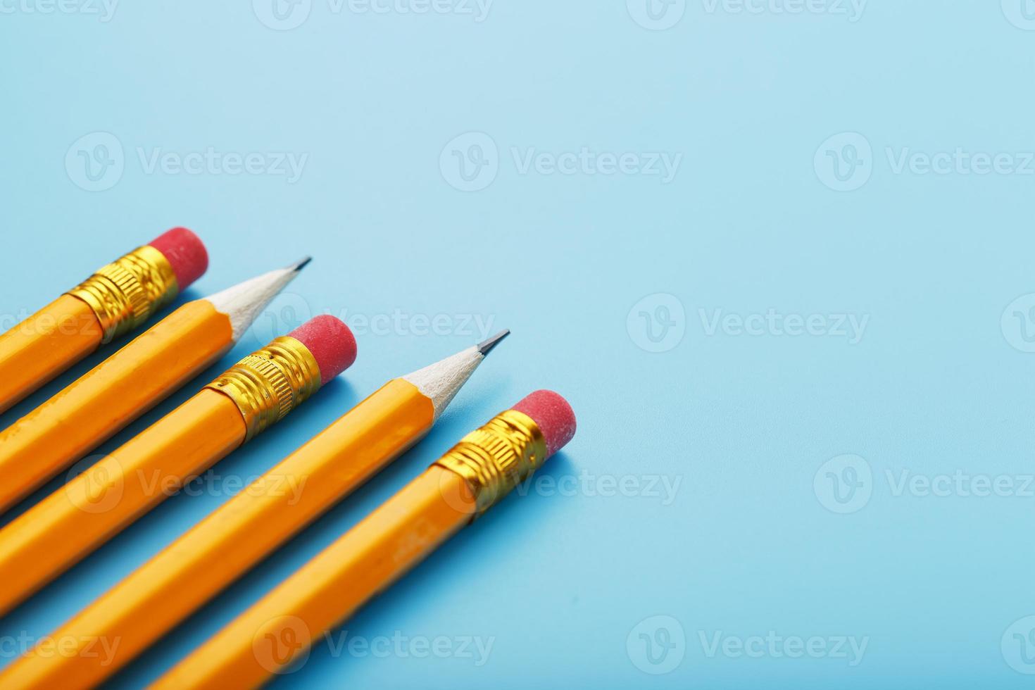 lápices naranjas con un borrador sobre un fondo azul. foto