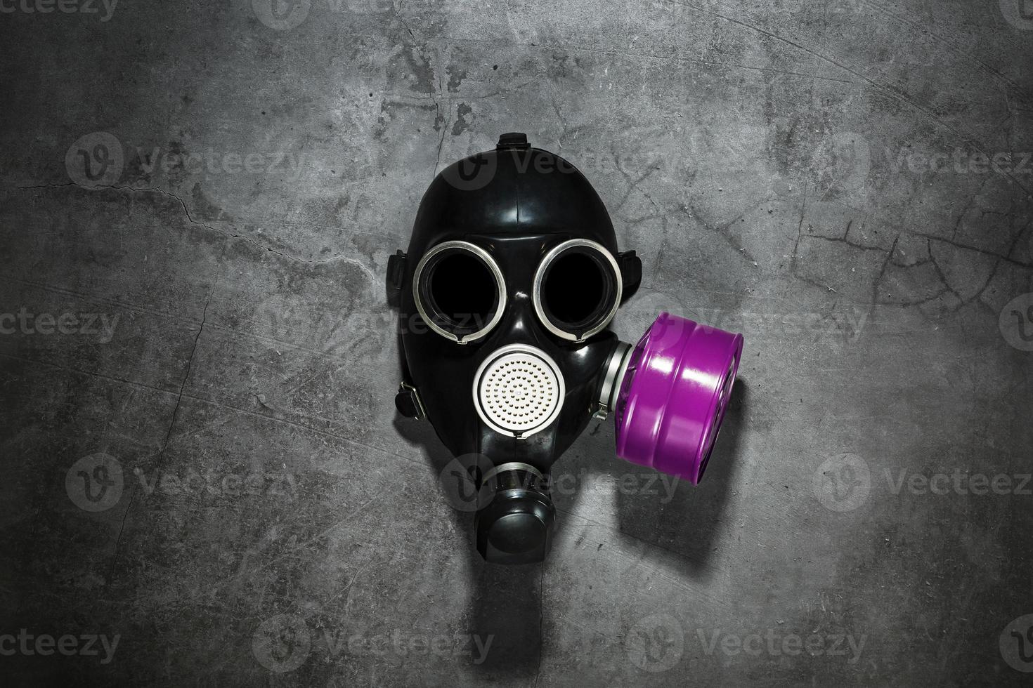 Gas mask on a black stone background with a pink filter cartridge. Post-apocalyptic concept. photo