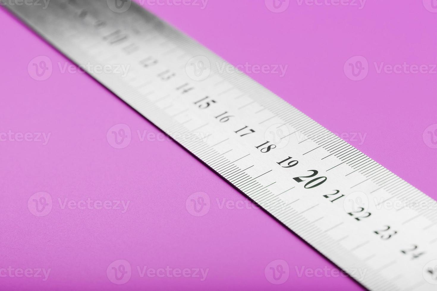 Metal ruler on a pink background close-up with a copy of the place for your text. photo