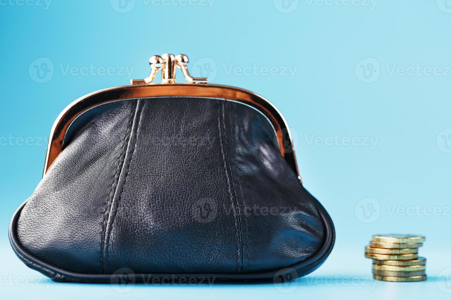 Black wallet with coins on a blue background. Budget for investment in the future. Free space, isolate, close-up photo