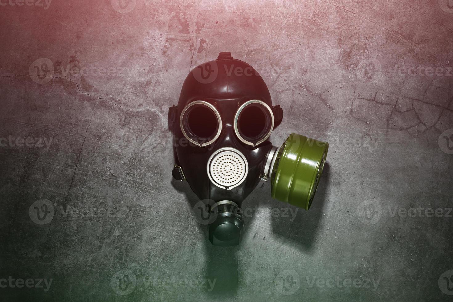 Gas mask on a black stone background with a green filter cartridge. Post-apocalyptic concept. photo