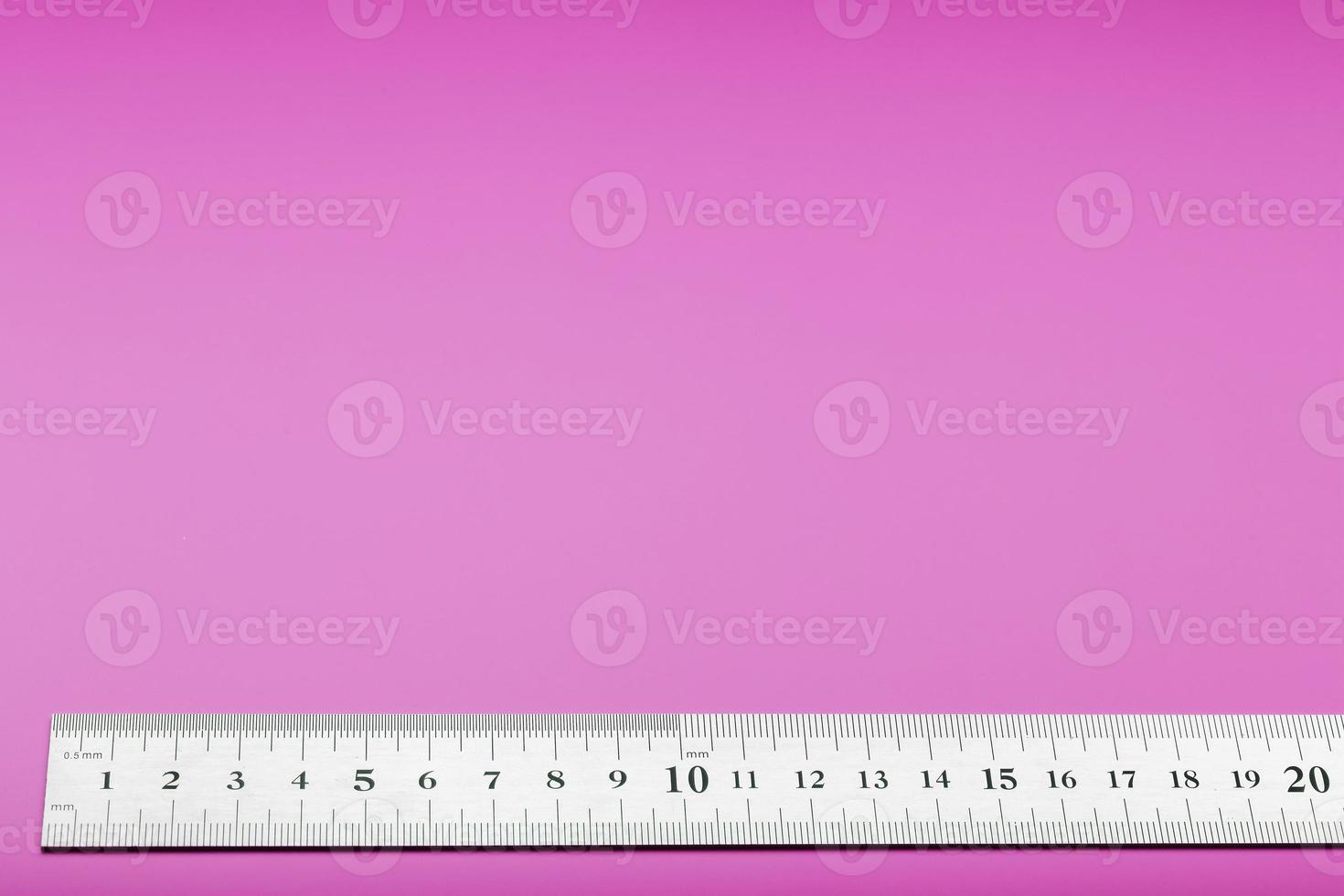 A metal ruler with a scale on a pink background is a superscape with a copy of the space for your text. photo