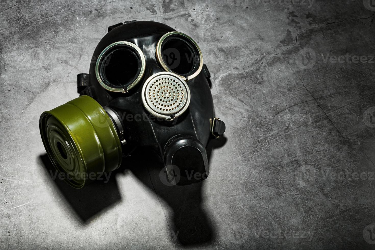 Gas mask on a black stone background with a green filter cartridge. Post-apocalyptic concept. photo