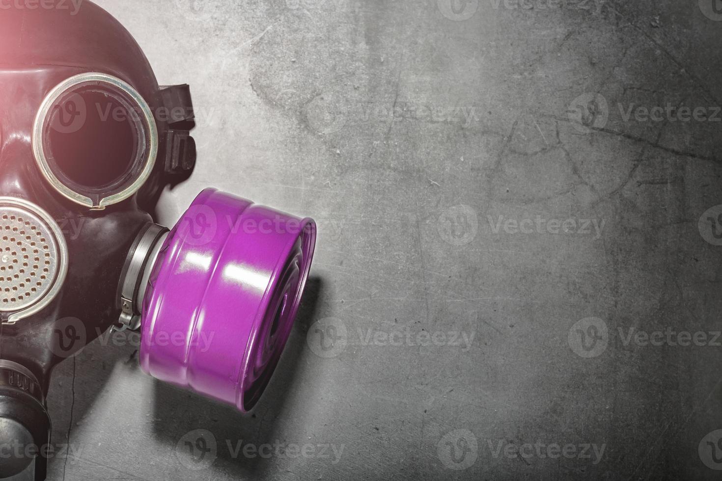 Gas mask on a black stone background with a pink filter cartridge. Post-apocalyptic concept. photo