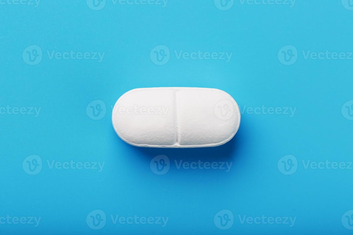 Medicinal tablet on a blue background, isolated. photo