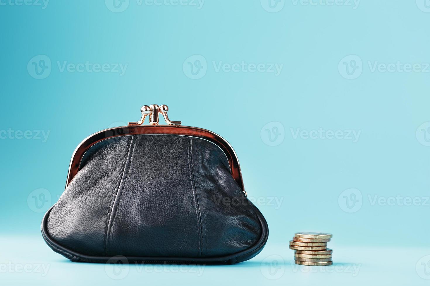 Black wallet with coins on a blue background. Budget for investment in the future. photo