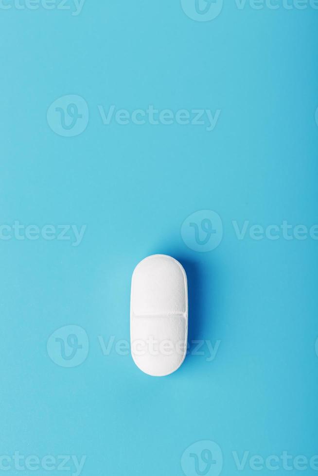 Medicinal tablet on a blue background, isolated. photo