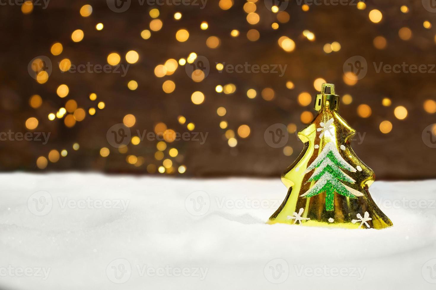 Golden Christmas tree on the snow with New Year's lights from behind. Blurred background. Christmas card photo