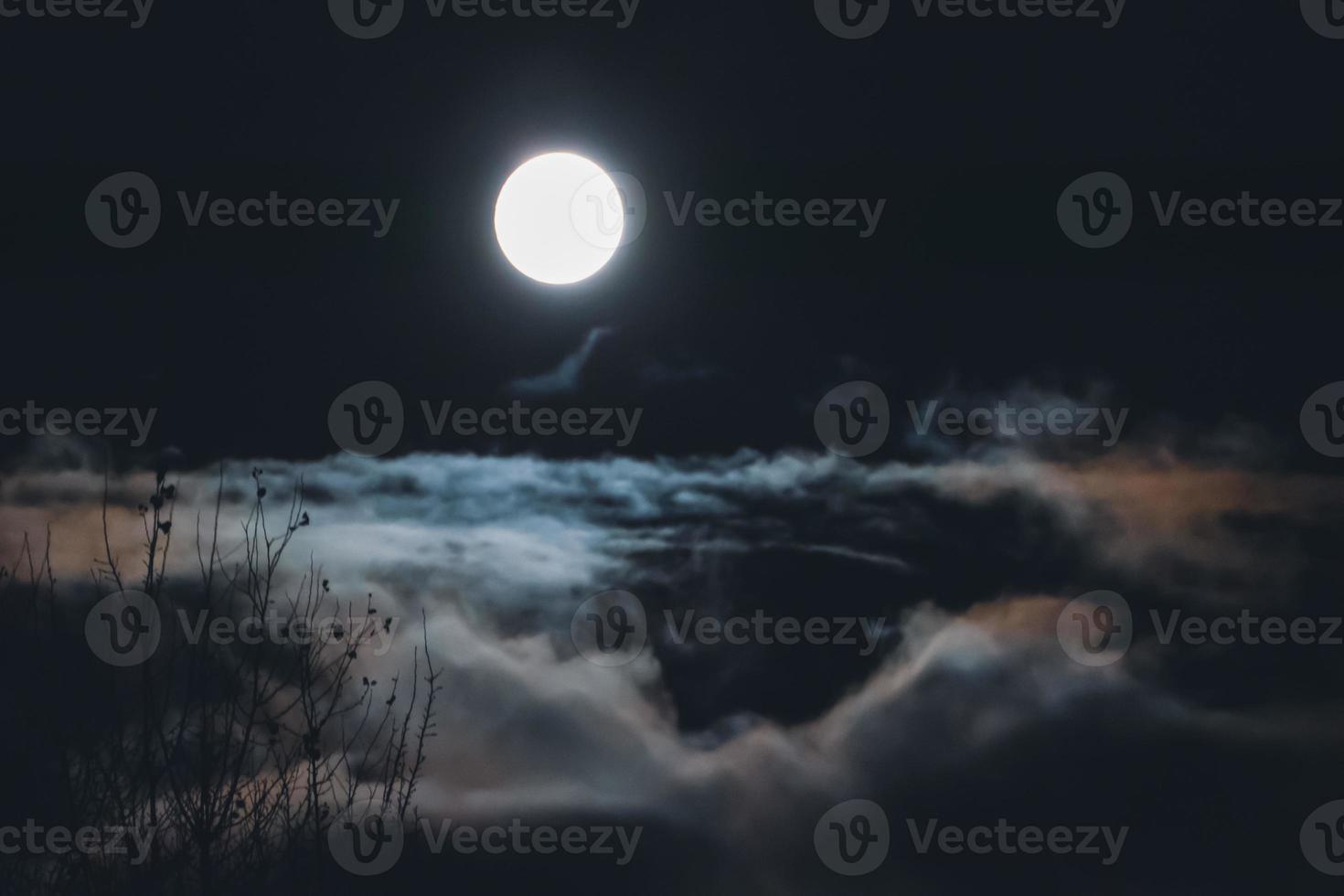 luna llena sobre nubes y niebla en el cielo nocturno, paisaje nebuloso y borroso foto
