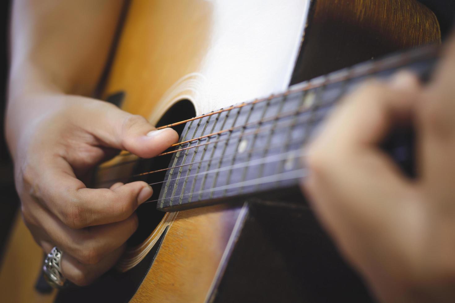 primer plano de la mano del hombre tocando la guitarra y detalles de la vieja guitarra acústica, línea y curva del instrumento, enfoque selectivo de cuerdas de guitarra con diapasón y cuello, concepto musical, fondo de guitarra foto