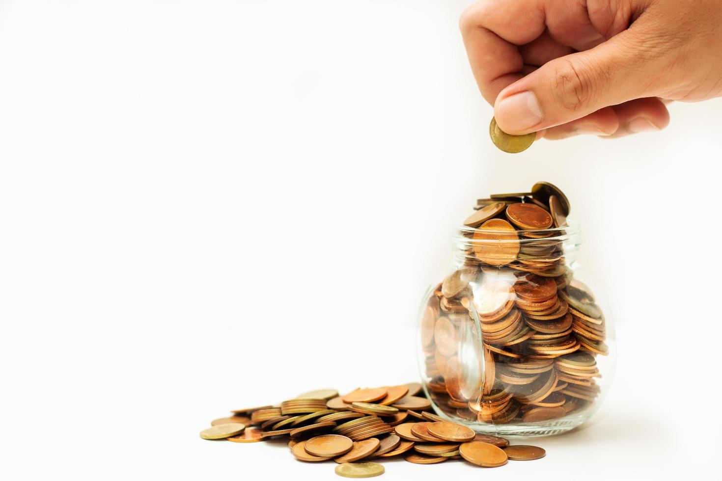 Man hand holding coin with many coins in bottle and a pile on white background, Money growing concept and sustainable investment, Business success and financial concept, Banking and economy idea photo