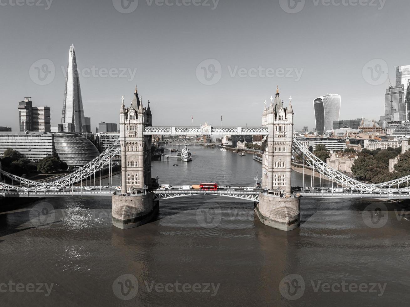 Beautiful black and white photo of London Tower bridge with an iconic red bus driving on it.