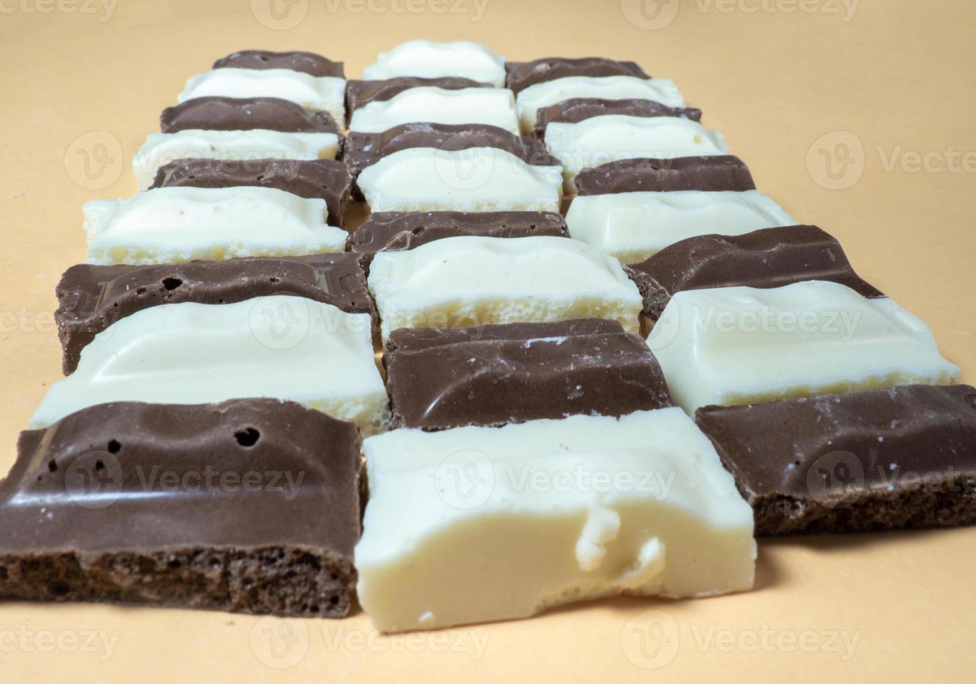 Slices of black and white chocolate on a biege background. Various chocolates on the table. photo