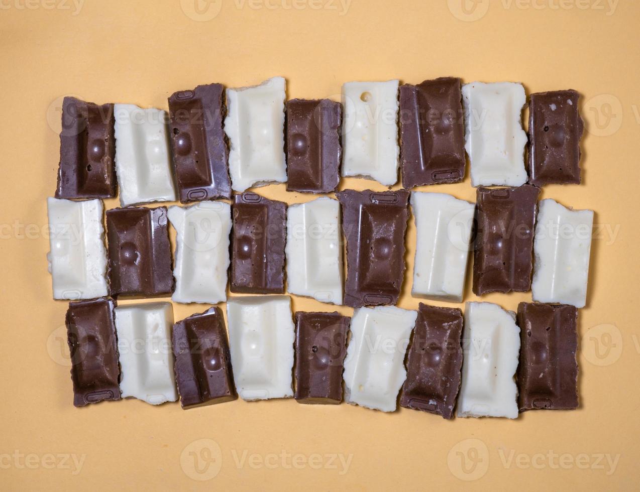 Slices of black and white chocolate on a beige background. Slices from a bar of chocolate. photo