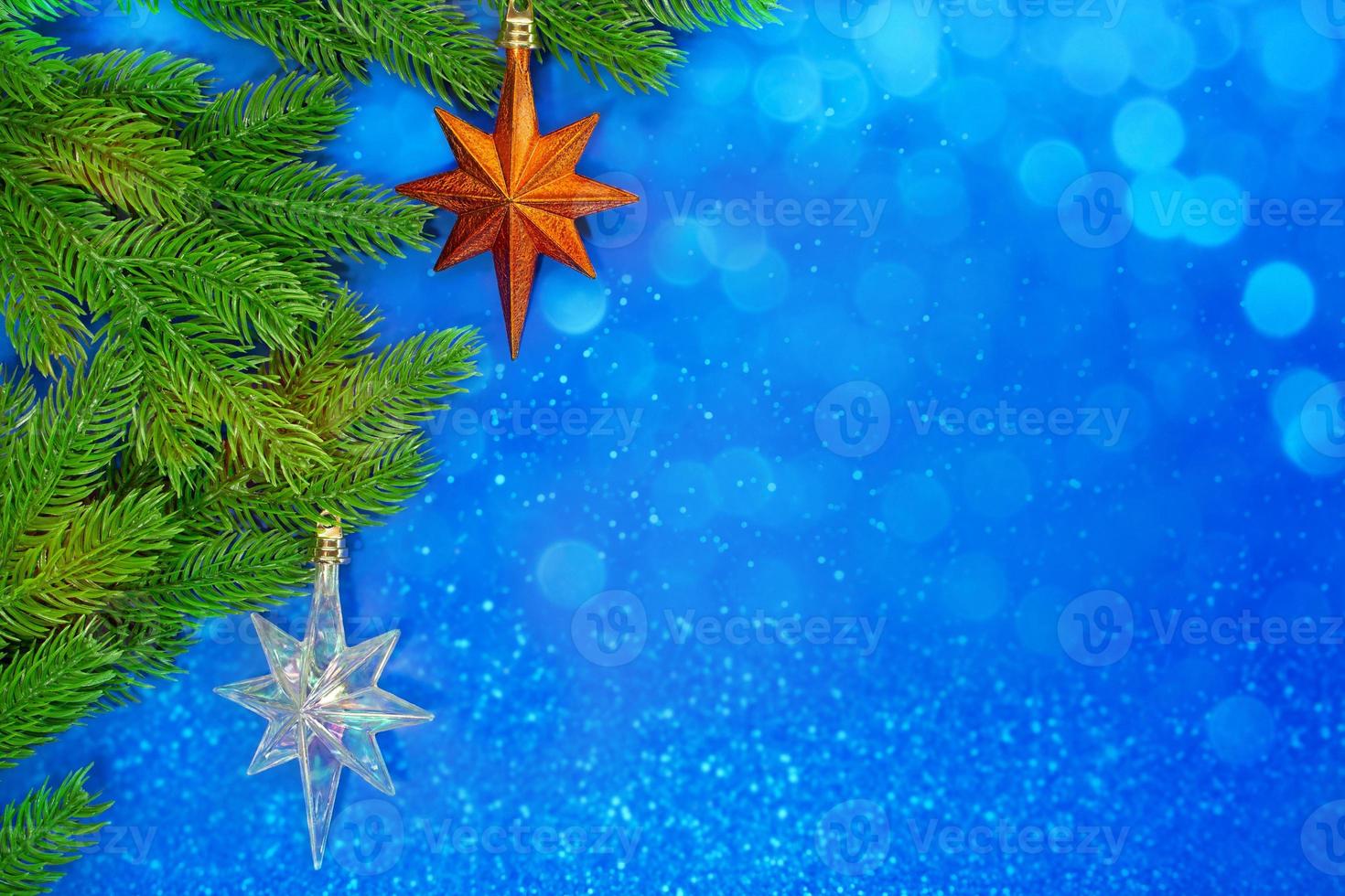 Pine branches with orange star and icy on blue background with bokeh. Christmas, New Year. Copy space photo