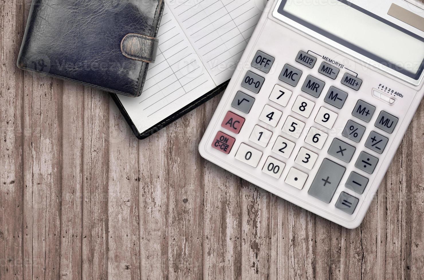 Office flat lay composition with calculator, address book and black purse on brown wooden table background with top view. Accountant paperwork concept photo