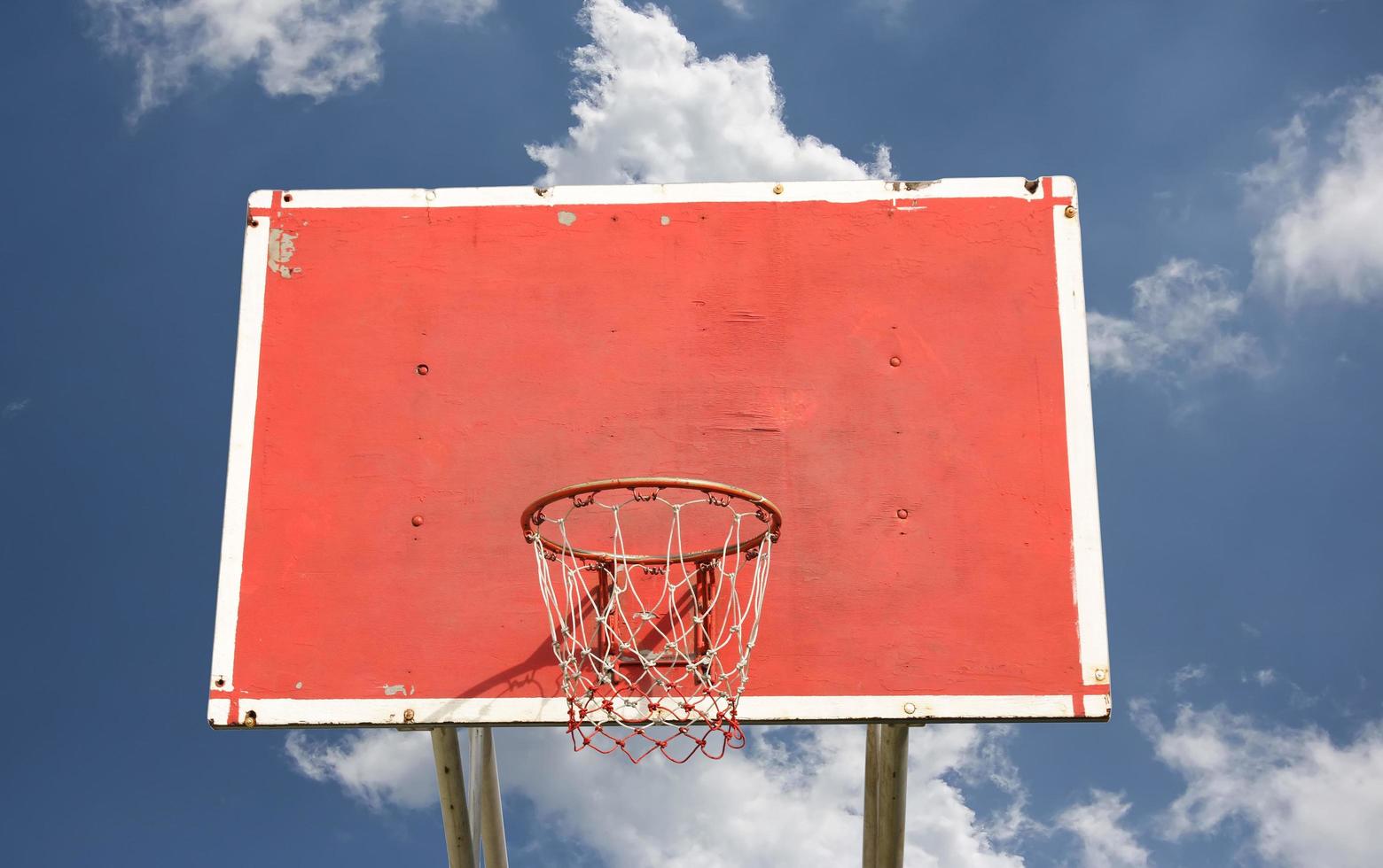 Outdoor basketball hoop with blue sky and clouds photo