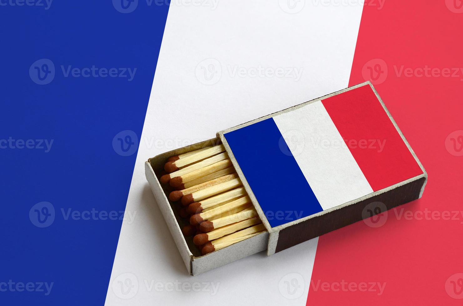 France flag  is shown in an open matchbox, which is filled with matches and lies on a large flag photo