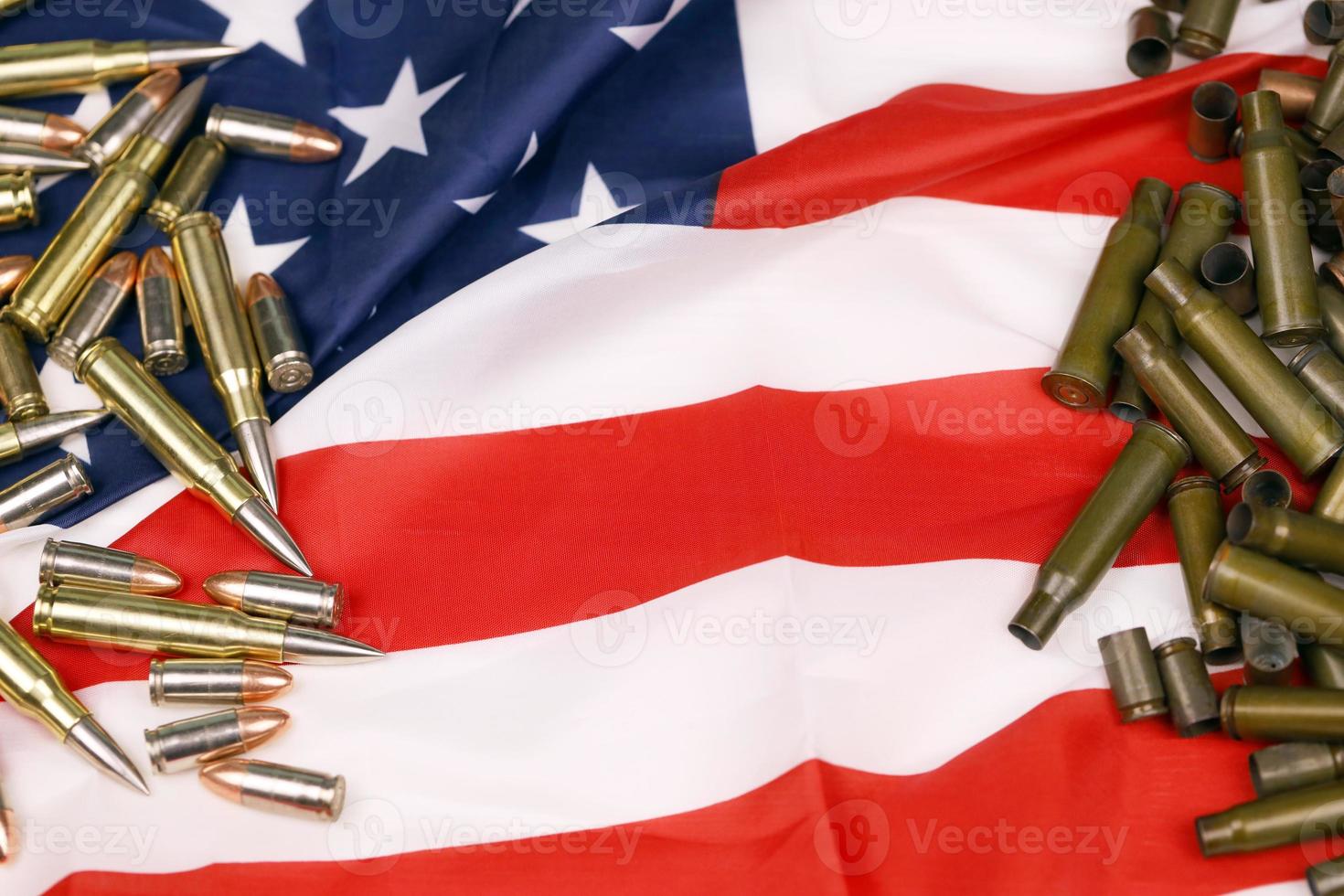 Many yellow 9mm and 5.56mm bullets and cartridges on United States flag. Concept of gun trafficking on USA territory or shooting range photo