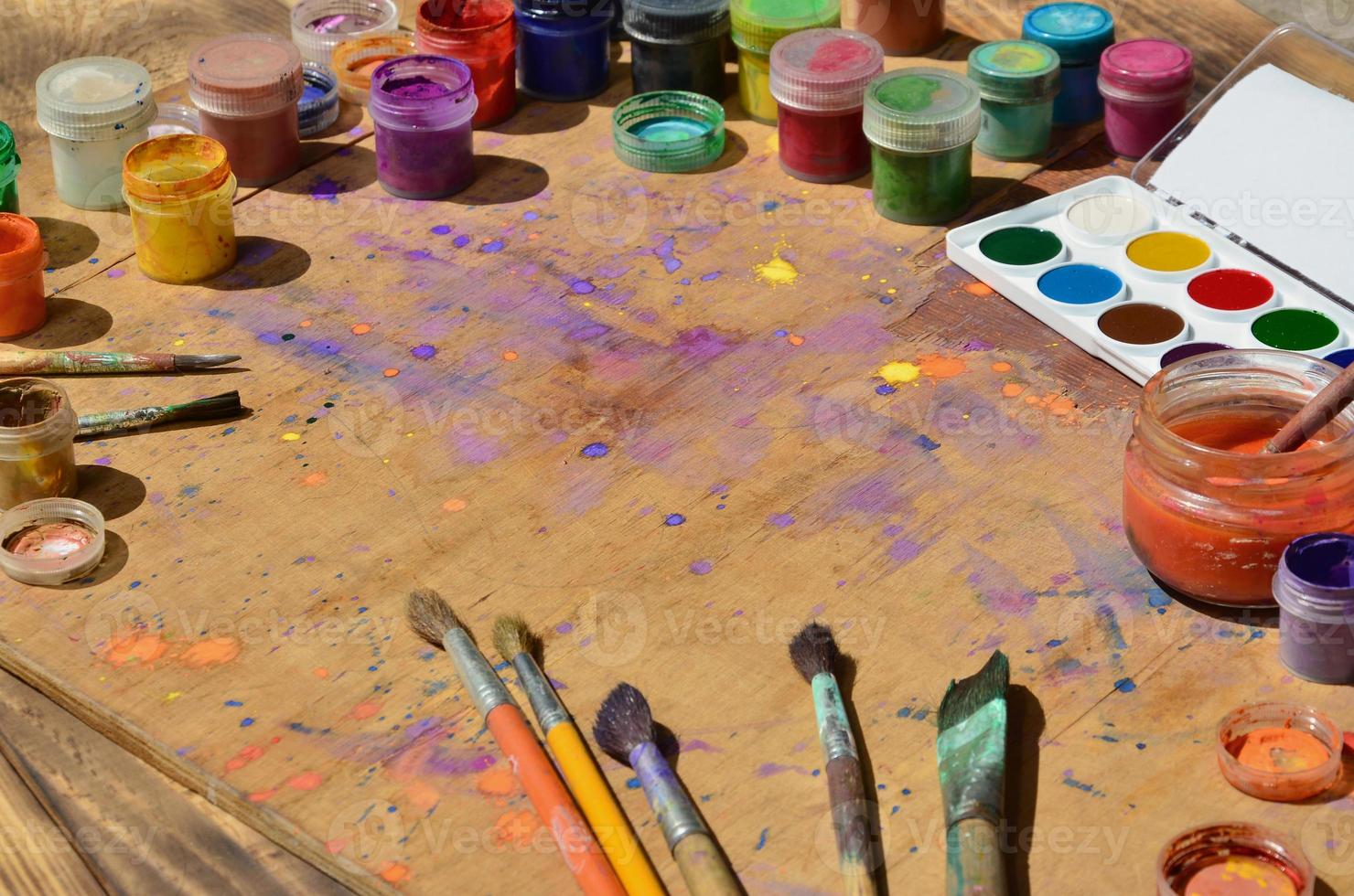 Still life with a lot of brushes and jars of watercolor and gouache paint photo