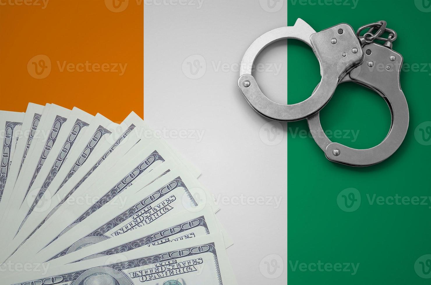 Ivory Coast flag  with handcuffs and a bundle of dollars. The concept of illegal banking operations in US currency photo