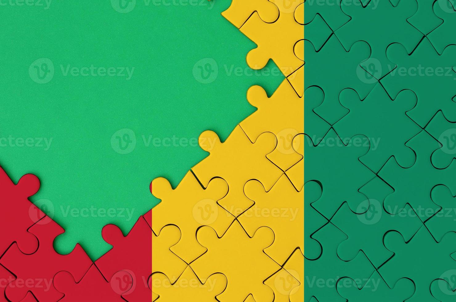 Guinea flag  is depicted on a completed jigsaw puzzle with free green copy space on the left side photo