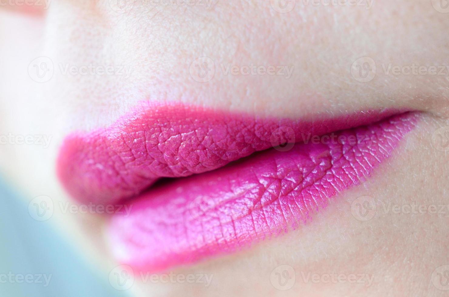 Close up shot of woman lips with glossy fuchsia lipstick photo