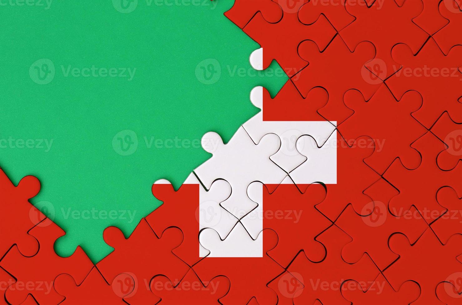 Switzerland flag  is depicted on a completed jigsaw puzzle with free green copy space on the left side photo
