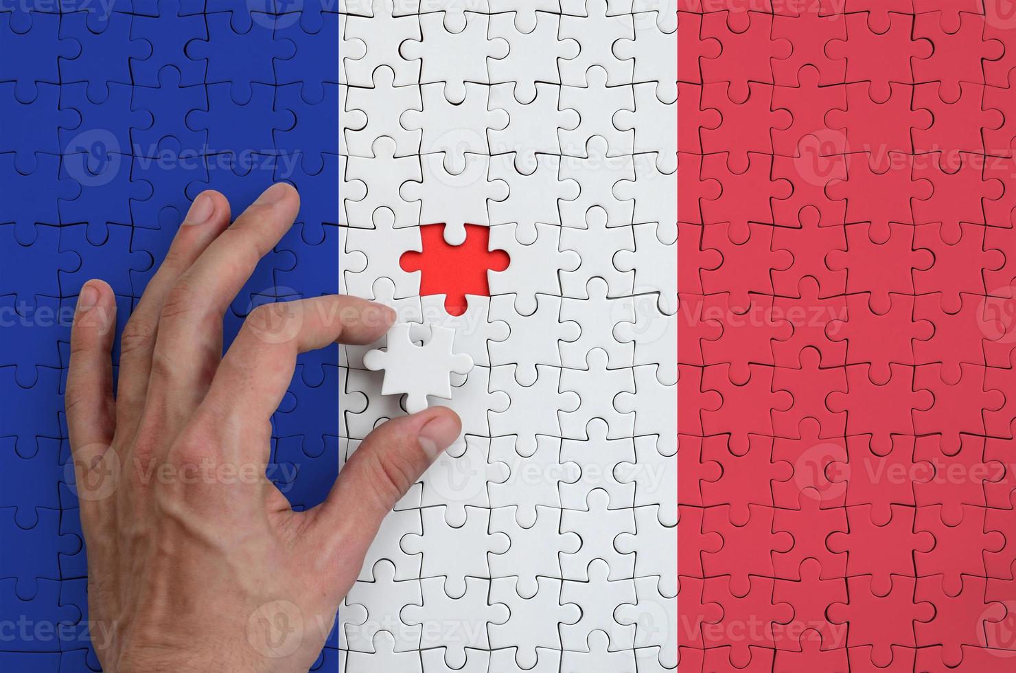 la bandera de francia está representada en un rompecabezas, que la mano del hombre completa para doblar foto